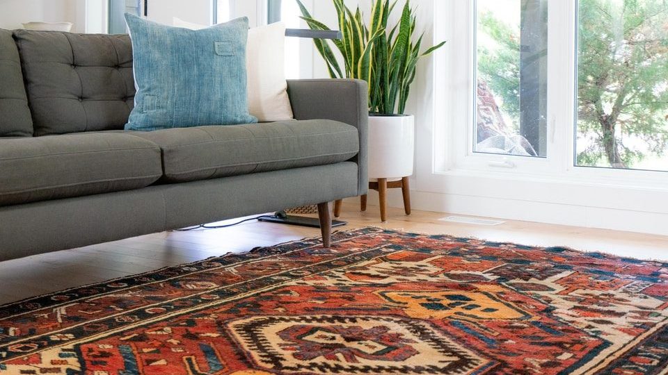 teal 2-seat couch and red area rug